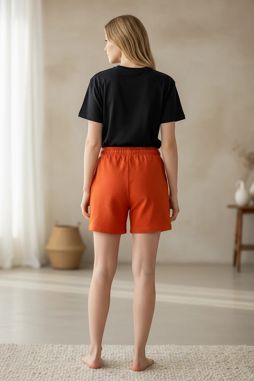 The Nile Luxuries lounge set featuring a black cotton t-shirt and vibrant orange elastic-waist shorts, back view.