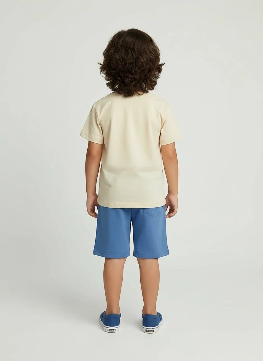 Back view of a boy wearing The Nile Luxuries cream t-shirt and blue shorts casual summer outfit set.