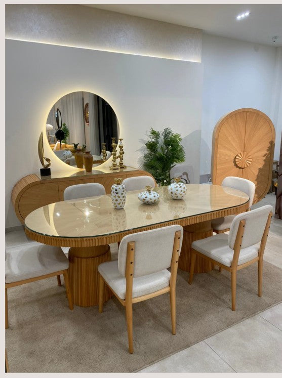 The Nile Luxuries oval dining table with fluted wood base, glass top, and upholstered chairs, paired with a mirrored buffet.
