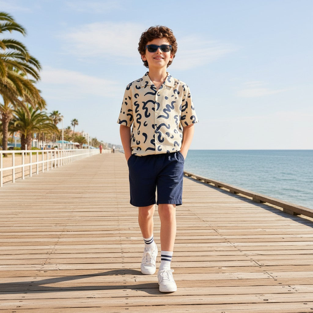 The Nile Luxuries short sleeve button-up shirt with abstract navy print on cream fabric, worn by a boy.