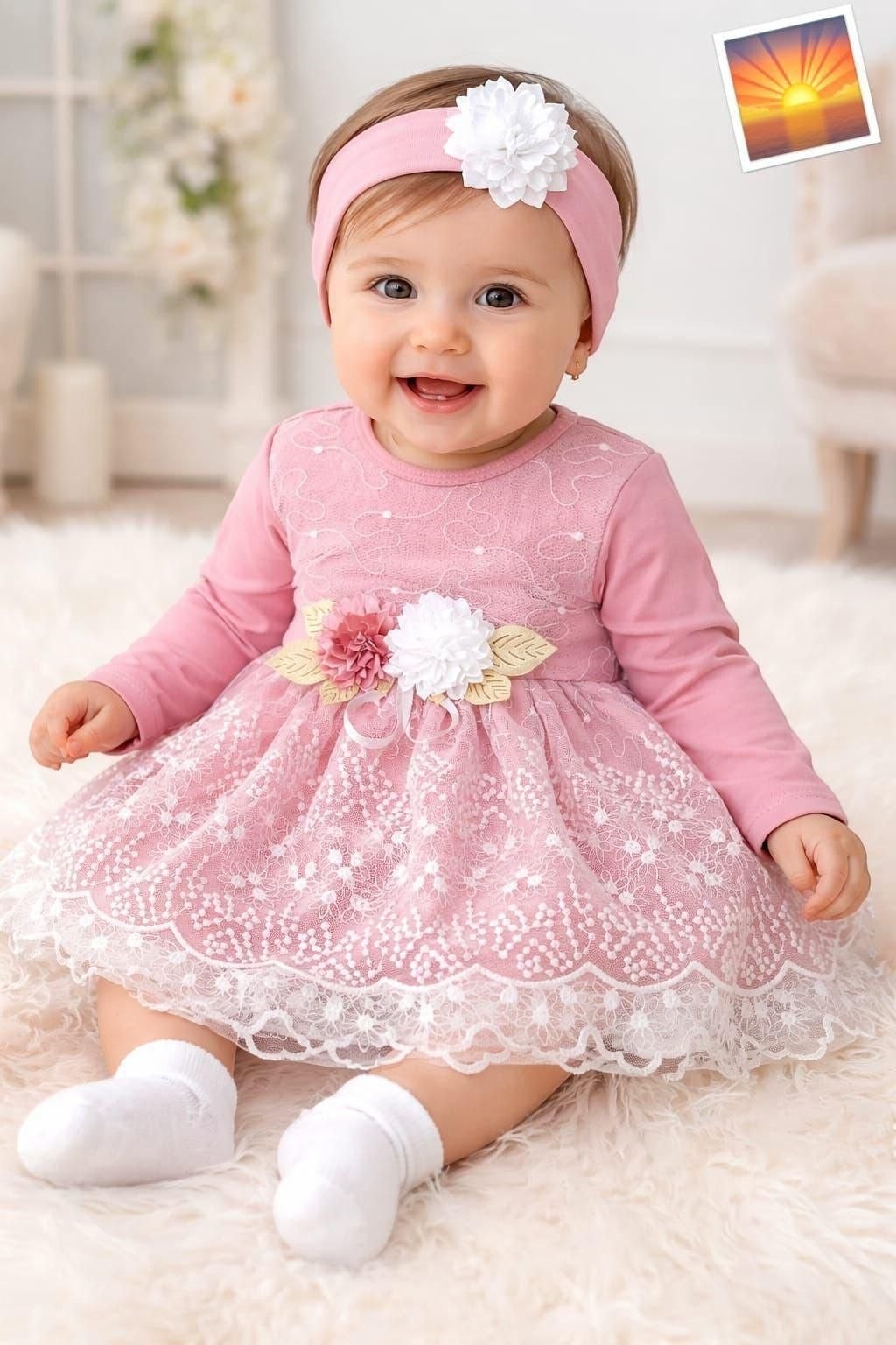 The Nile Luxuries baby girl pink lace dress with floral waist appliqué and matching headband. Long sleeves, scalloped hem.