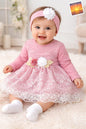 The Nile Luxuries baby girl pink lace dress with floral waist appliqué and matching headband. Long sleeves, scalloped hem.