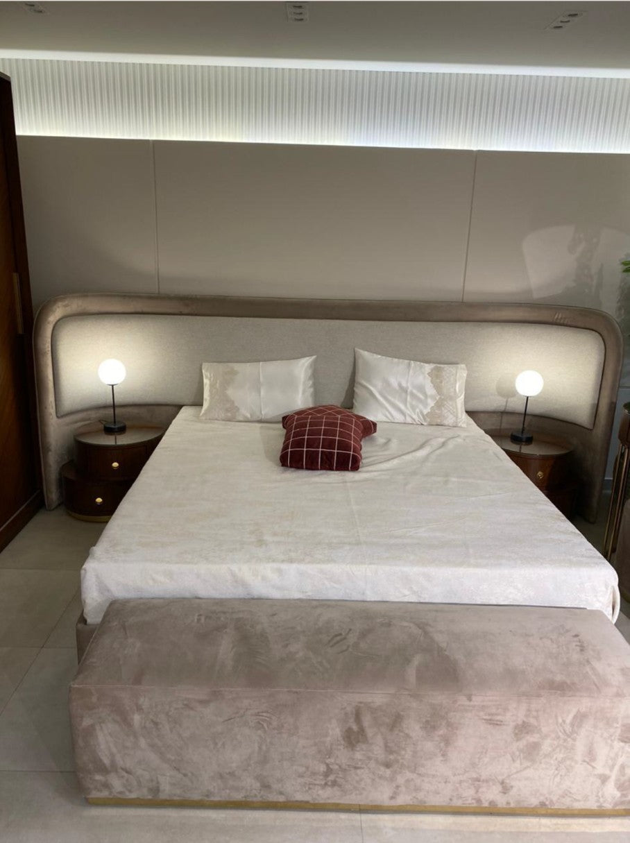 The Nile Luxuries contemporary bedroom set featuring a plush upholstered bed with a curved headboard, two bedside tables, and a velvet bench.