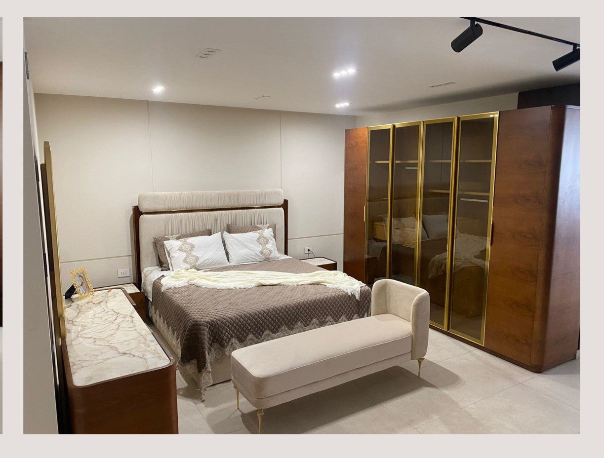 The Nile Luxuries upholstered bed with channel tufted headboard, neutral fabric, and matching bench and wardrobe.