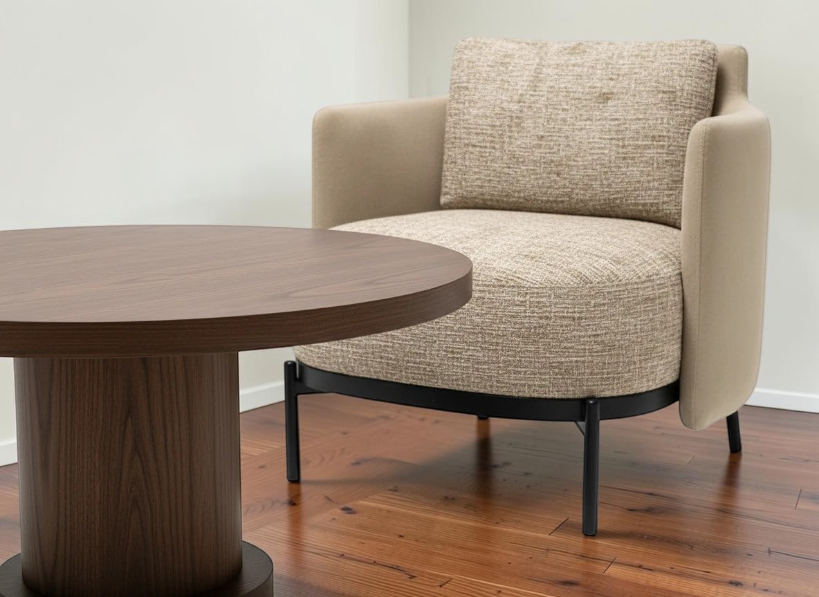 The Nile Luxuries modern armchair upholstered in textured beige fabric with a round wooden coffee table.