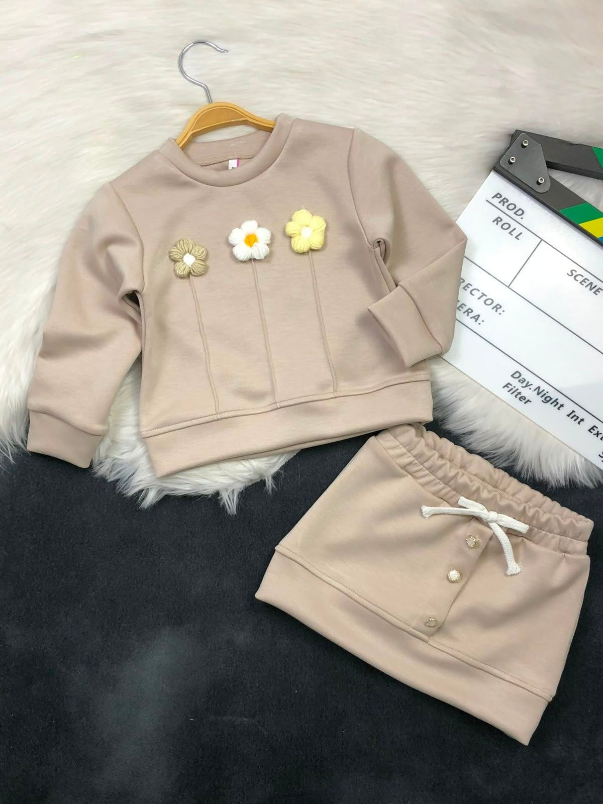 The Nile Luxuries girls beige sweatshirt and skirt set with textured floral appliques and decorative front buttons.