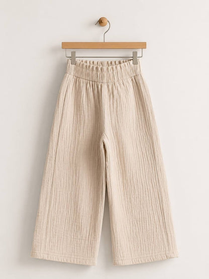 The Nile Luxuries beige wide-leg trousers in crinkled cotton muslin with a high-rise elasticated waistband.