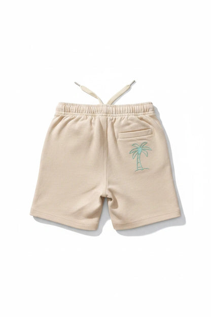The Nile Luxuries beige cotton shorts with an elastic drawstring waistband and sage green palm tree embroidery.