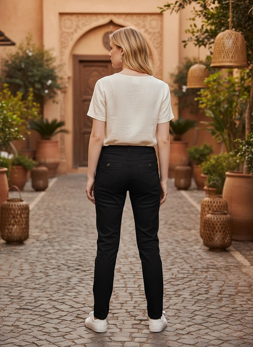The Nile Luxuries black chino trousers worn by a woman with a white top, featuring a classic fit and back pockets.