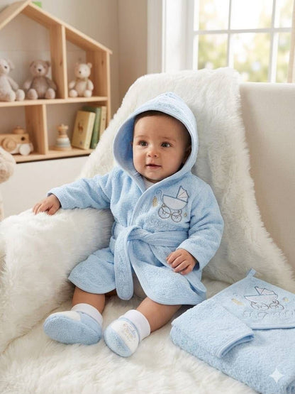 Baby wearing a light blue The Nile Luxuries plush hooded bathrobe and matching slippers with embroidered pram design