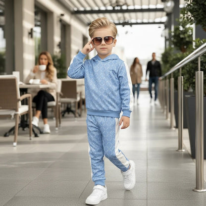 The Nile Luxuries light blue geometric print hoodie and jogger set worn by a young boy with sunglasses on a patio.