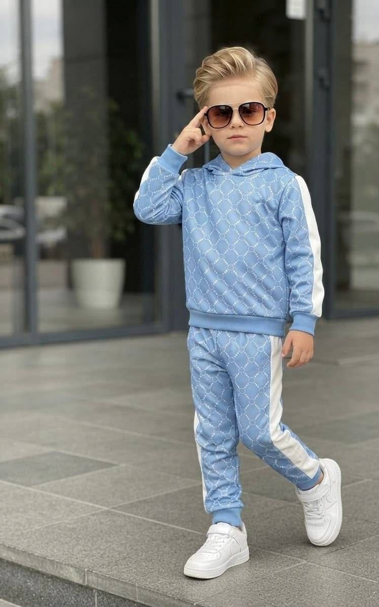 A young boy wearing The Nile Luxuries light blue geometric print hoodie and jogger set with white side stripes.