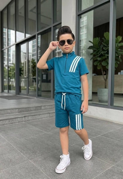 A boy wearing a teal The Nile Luxuries athletic short set with a quarter-zip top and triple-stripe detailing.