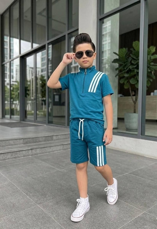 A boy wearing a teal The Nile Luxuries athletic short set with a quarter-zip top and triple-stripe detailing.