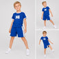 A young boy wearing The Nile Luxuries blue short-sleeve t-shirt and shorts set with white side stripes and Hi graphic.