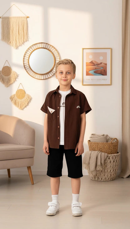 The Nile Luxuries boys brown short-sleeve camp collar shirt with triangular pocket detail, worn over a white tee.