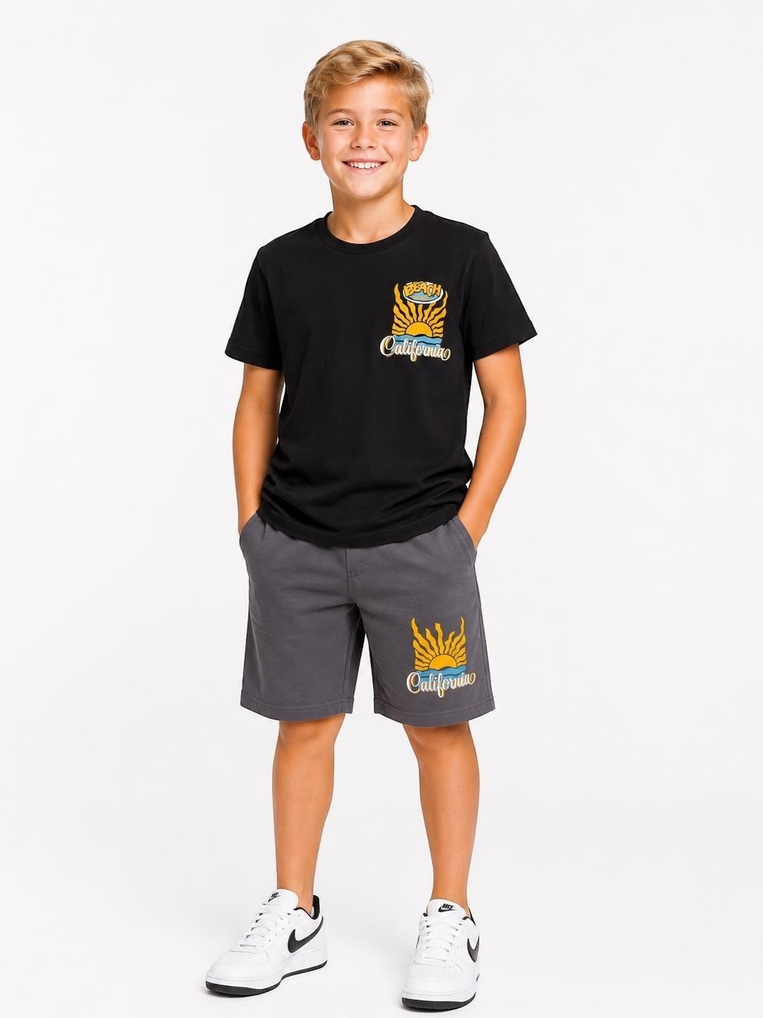 A young boy wearing a black The Nile Luxuries California graphic t-shirt and grey cotton shorts set.