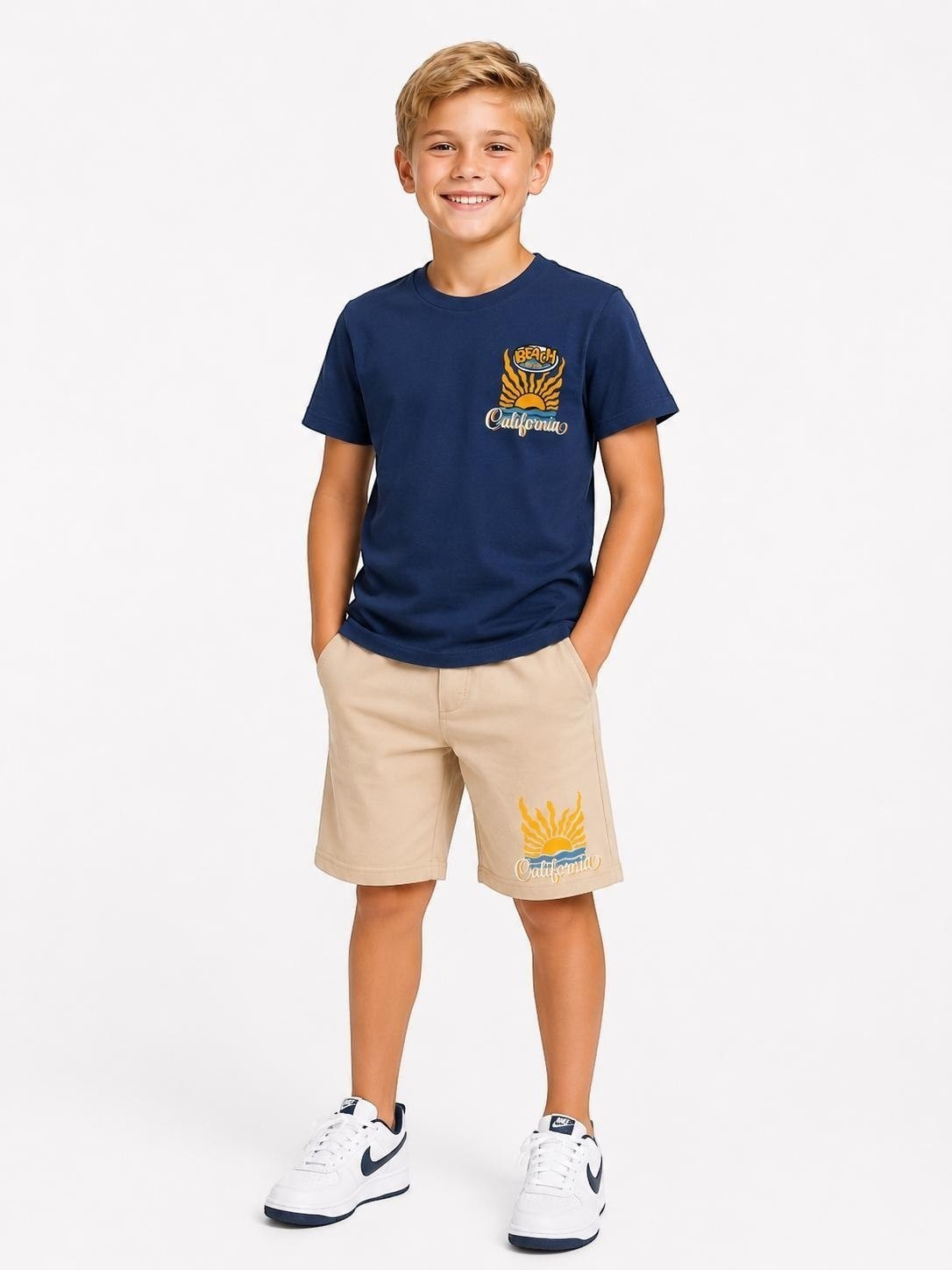 A young boy wearing a The Nile Luxuries navy blue California graphic t-shirt and beige shorts set.
