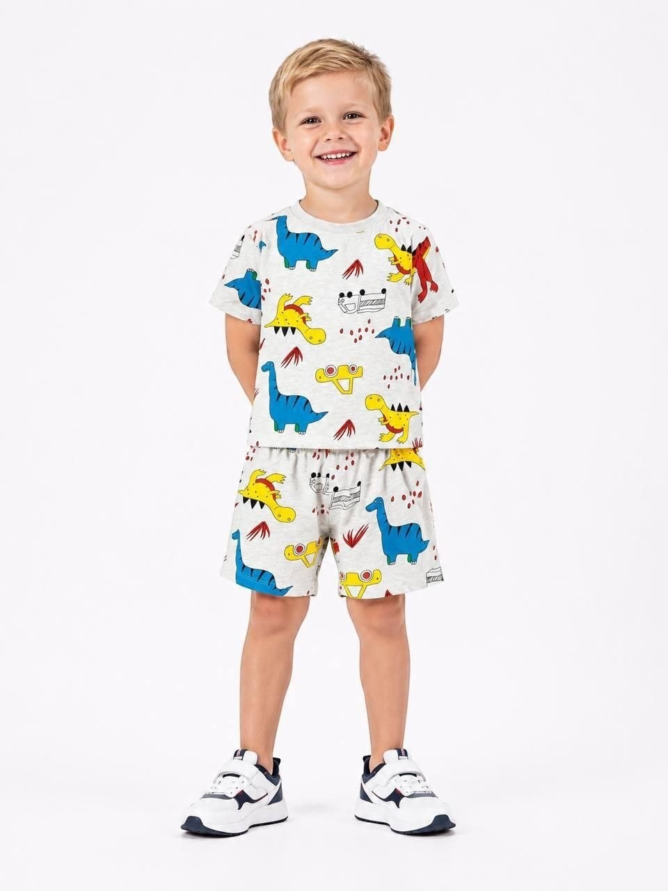 Young boy wearing The Nile Luxuries grey short-sleeve t-shirt and shorts set with colorful dinosaur print.