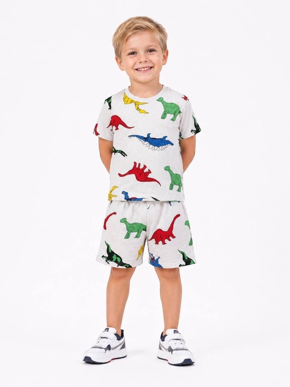 Young boy wearing The Nile Luxuries grey short sleeve t-shirt and shorts set with a colorful dinosaur print.