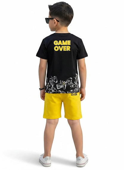 The Nile Luxuries boy wearing a black Game Over graphic t-shirt and yellow shorts with gaming controller prints.