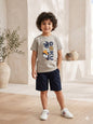 The Nile Luxuries boy wearing a grey Dragon Ball Z Goku graphic t-shirt with navy shorts and white sneakers.