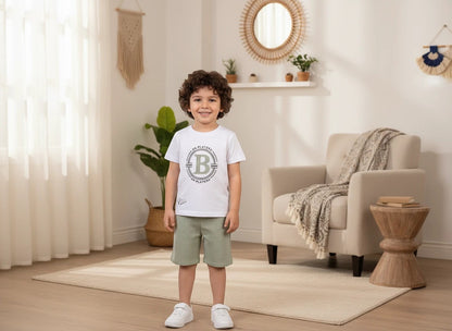 The Nile Luxuries boys white graphic t-shirt and sage green textured shorts outfit set worn by a young boy.