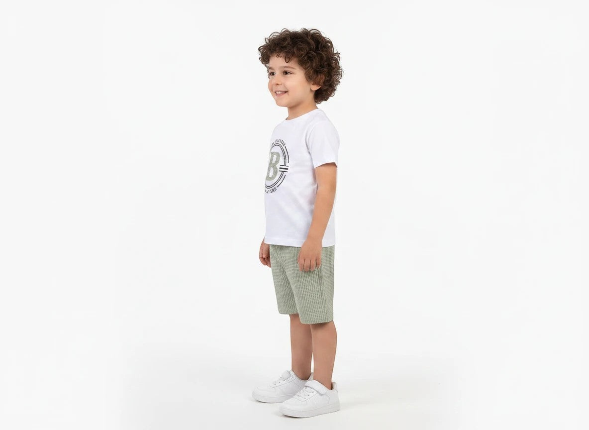 The Nile Luxuries boys white graphic t-shirt and sage green textured shorts outfit set worn by a young boy