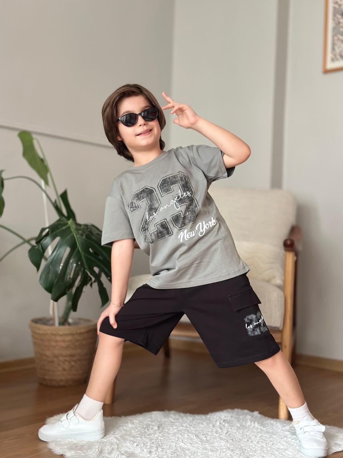 The Nile Luxuries boys grey graphic t-shirt and black cargo shorts set worn by a boy with sunglasses