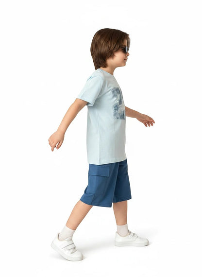 The Nile Luxuries boys light blue graphic t-shirt and dark blue cargo shorts set worn by a child in profile view