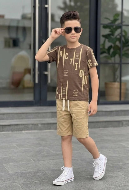 Boy wearing The Nile Luxuries brown graphic t-shirt and beige shorts with white sneakers and sunglasses outdoors.