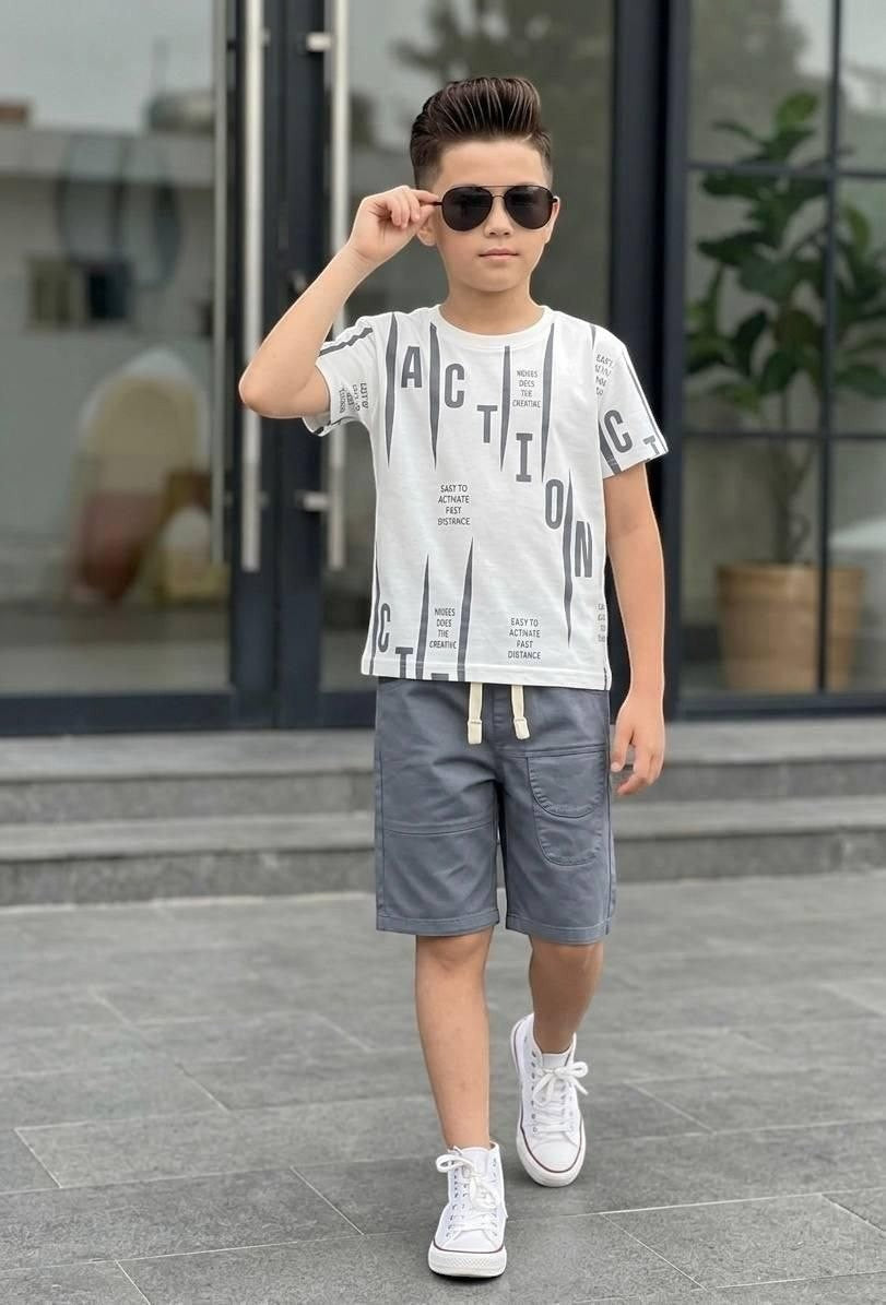 The Nile Luxuries boys' white graphic t-shirt and grey shorts set with drawstring waist and white sneakers.