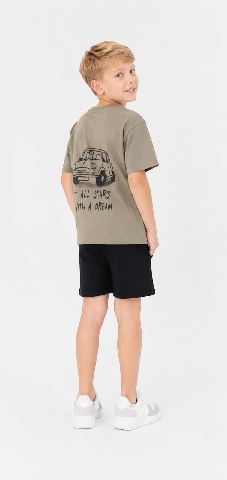 A boy wearing a khaki The Nile Luxuries cotton t-shirt with a car graphic and It All Starts With A Dream text.