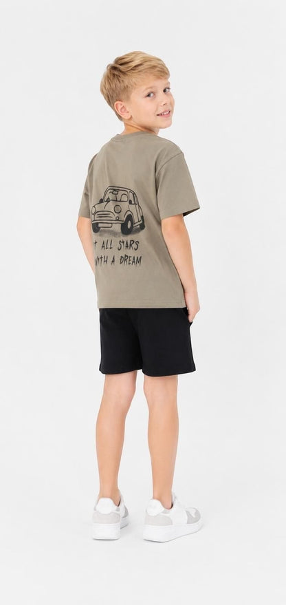 A boy wearing a khaki The Nile Luxuries cotton t-shirt with a car graphic and It All Starts With A Dream text.