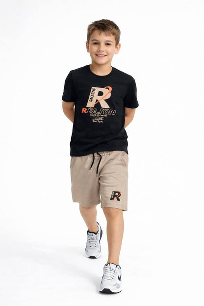 A boy wearing a The Nile Luxuries black graphic t-shirt and beige drawstring shorts set with athletic sneakers.