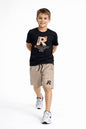 A boy wearing a The Nile Luxuries black graphic t-shirt and beige drawstring shorts set with athletic sneakers.