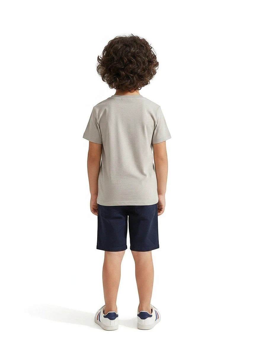The Nile Luxuries boys grey short sleeve crew neck t-shirt worn with navy shorts and white sneakers, back view.