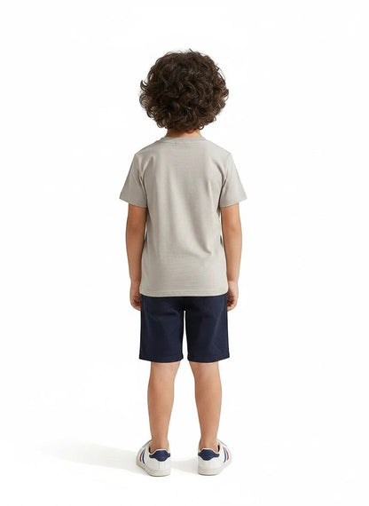 The Nile Luxuries boys grey short sleeve crew neck t-shirt worn with navy shorts and white sneakers, back view.