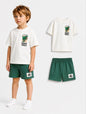 The Nile Luxuries Boys Jurassic World graphic tee and green shorts set. Off-white cotton t-shirt with dinosaur graphic. Green shorts with elastic waist.