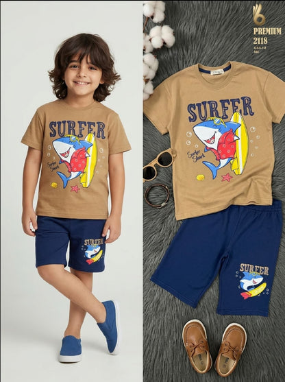 The Nile Luxuries boys tan t-shirt and navy shorts set featuring a fun shark surfer graphic print for summer wear.