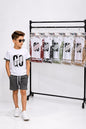 The Nile Luxuries boys summer outfit with white GO graphic t-shirt and black checkered shorts worn by a young boy