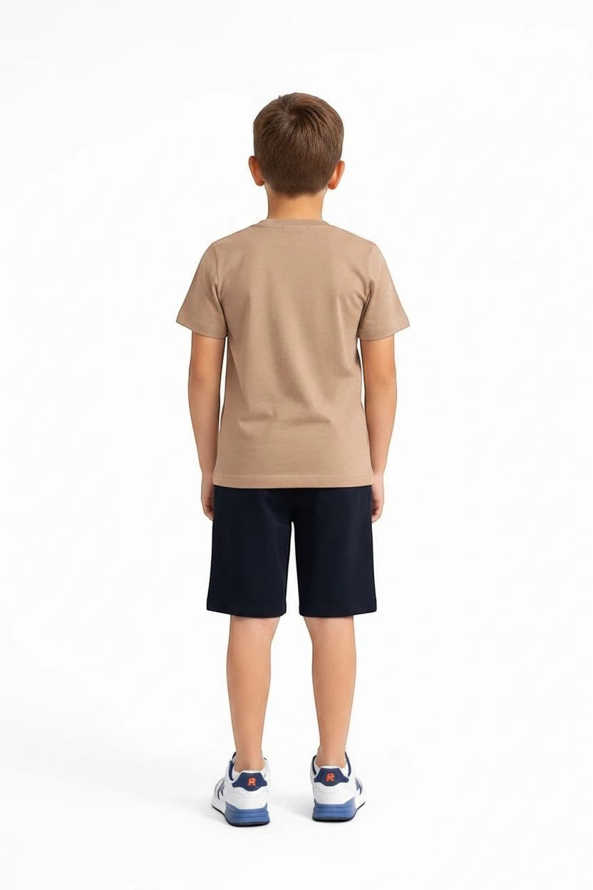 Back view of a boy wearing The Nile Luxuries tan t-shirt and navy blue athletic shorts with sneakers.