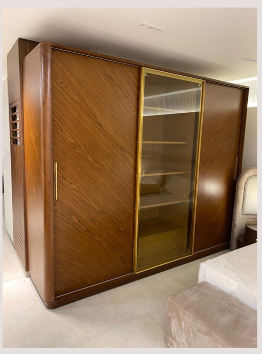 The Nile Luxuries contemporary wood wardrobe with diagonal grain, gold frame sliding doors, and smoked glass panel.