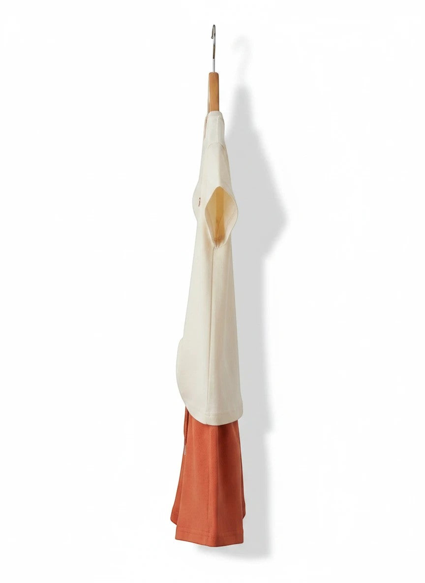 The Nile Luxuries children's casual t-shirt and shorts set in cream and terracotta, hanging on a wooden hanger.