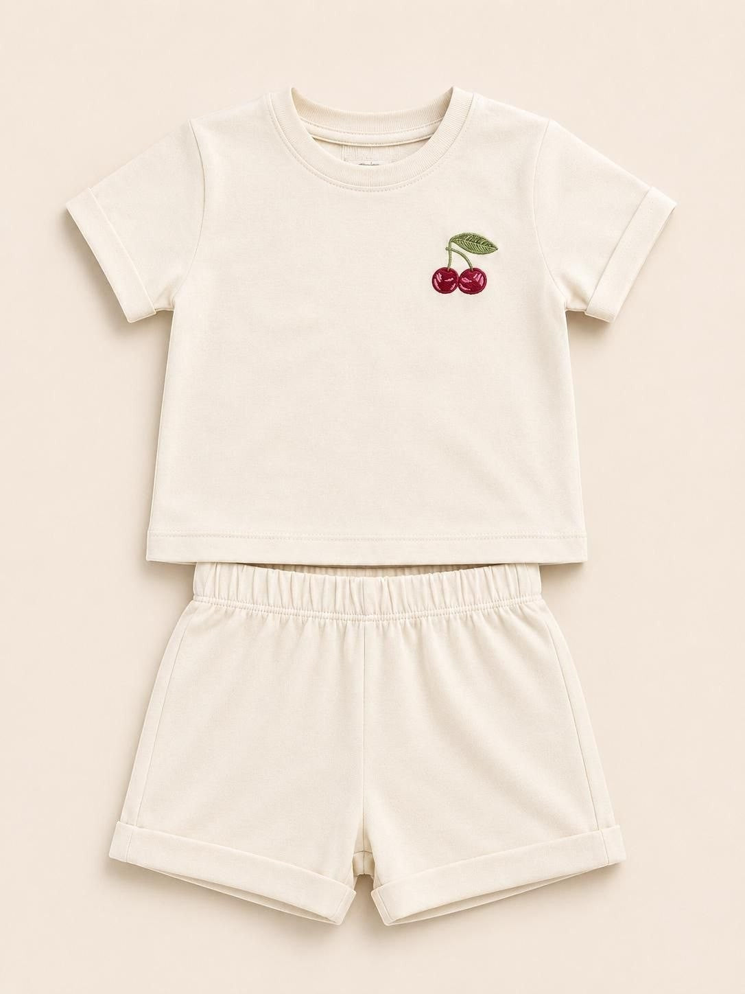 The Nile Luxuries toddler cream short sleeve t-shirt and shorts set with embroidered cherry detail and cuffed hems.