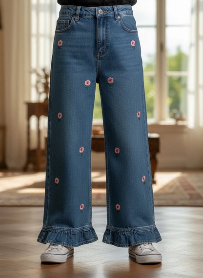 The Nile Luxuries blue denim wide-leg trousers featuring pink floral embroidery and a ruffled hem for girls.