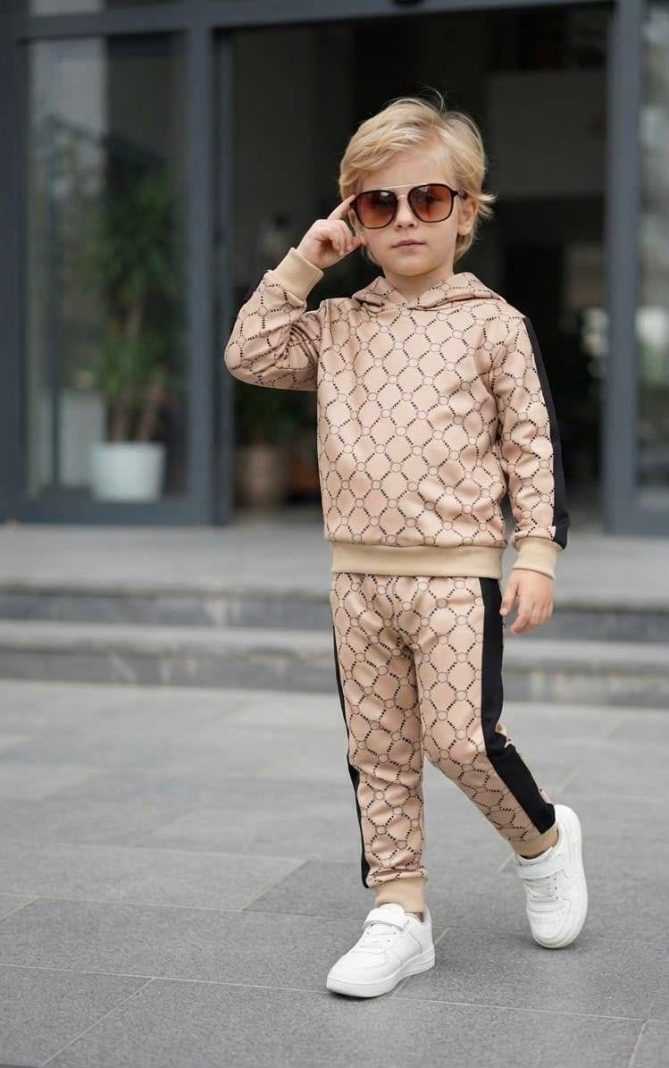 The Nile Luxuries children's beige geometric print hoodie and jogger set with black side stripes worn by a young boy.