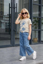 The Nile Luxuries: Girl in beige t-shirt with star graphic and distressed denim jeans with star patches.
