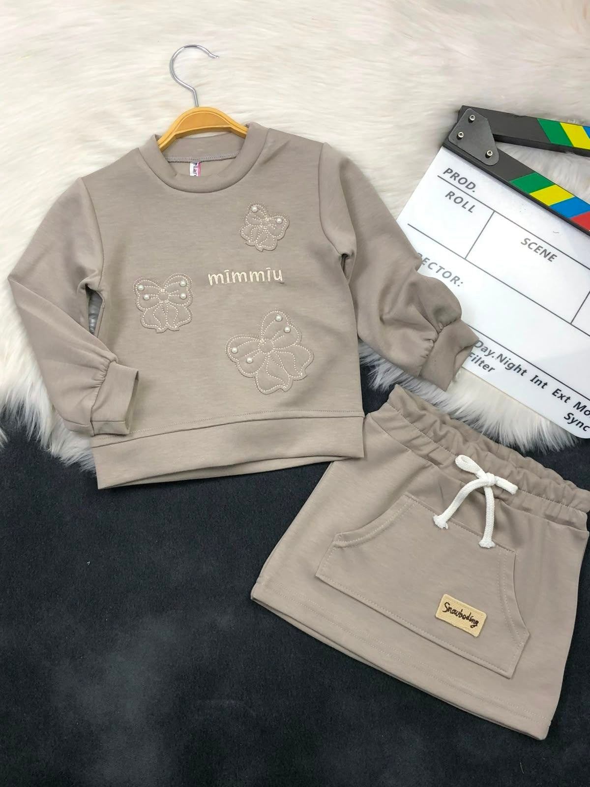 The Nile Luxuries girls beige sweatshirt and skirt set with butterfly embroidery, pearl accents, and front pocket.