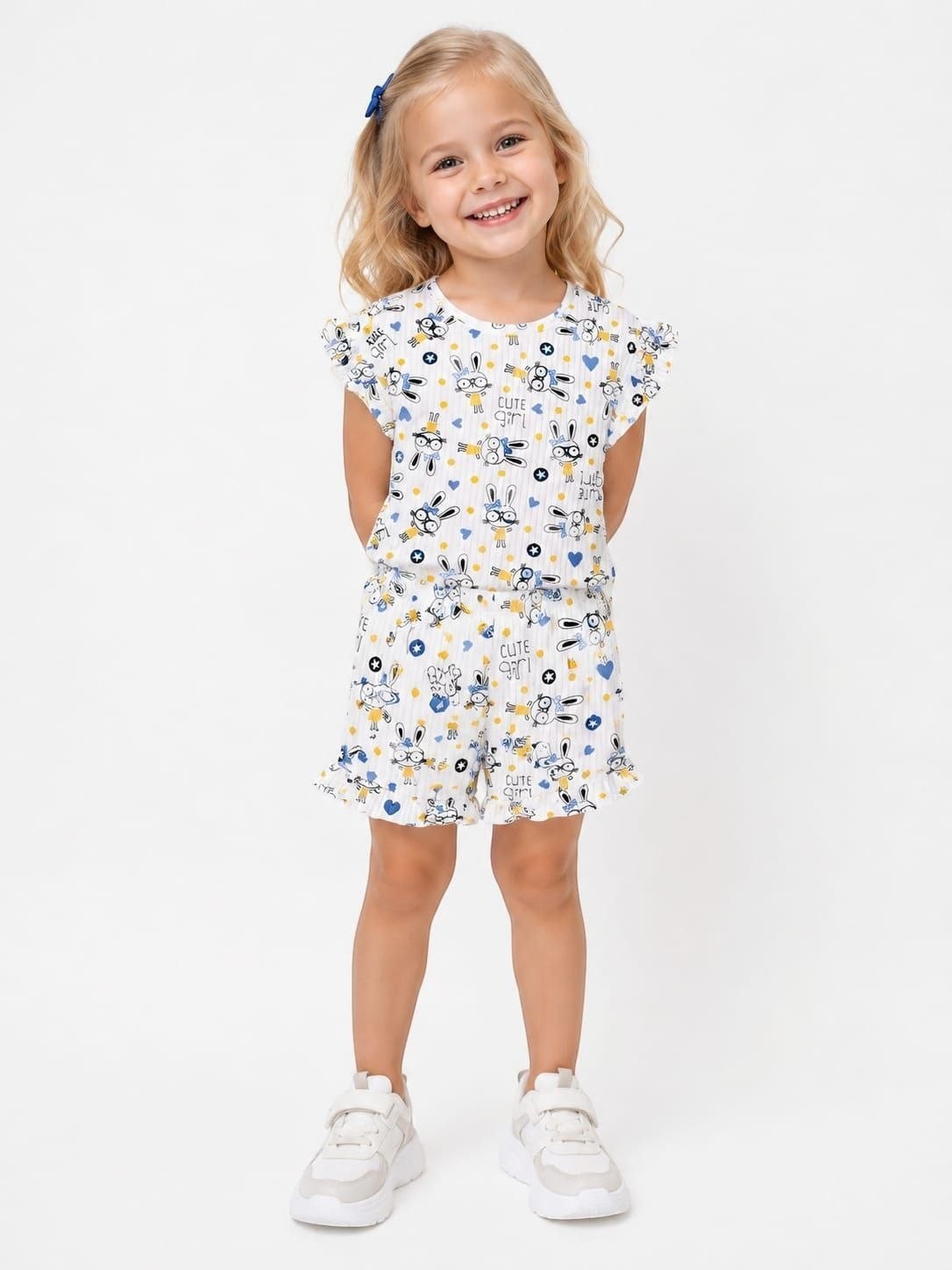 A young girl wearing The Nile Luxuries white ruffle lounge set with a cute bunny print, flutter sleeves, and shorts.